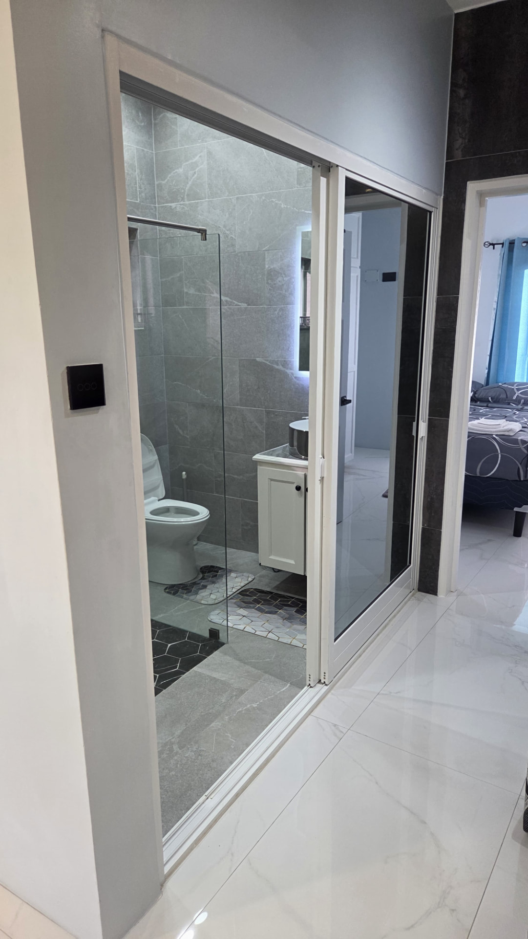 Glass-walled en-suite bathroom seen from the hallway